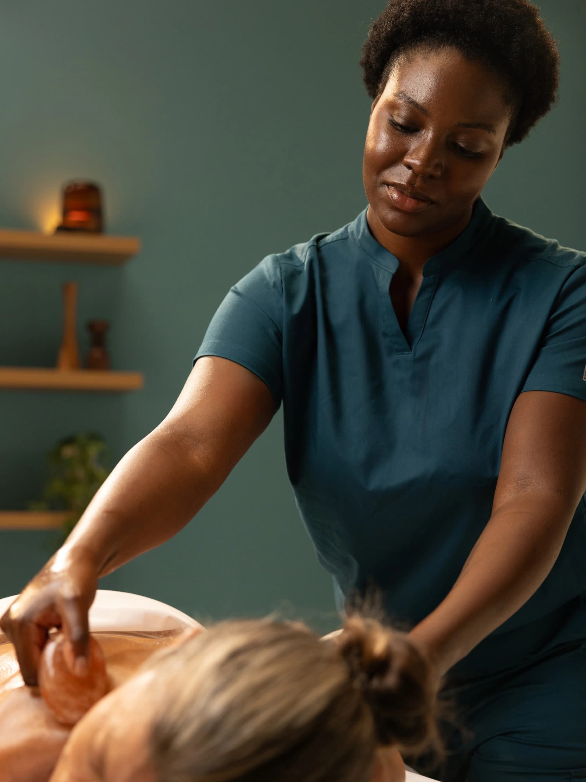 Licensed massage therapist performing a massage in a calm, softly lit treatment room