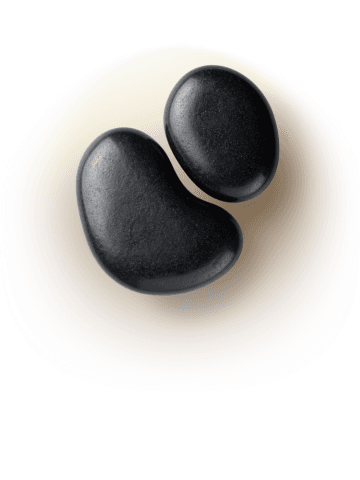 Two smooth black basalt stones used as an enhancement to a massage on a soft neutral background