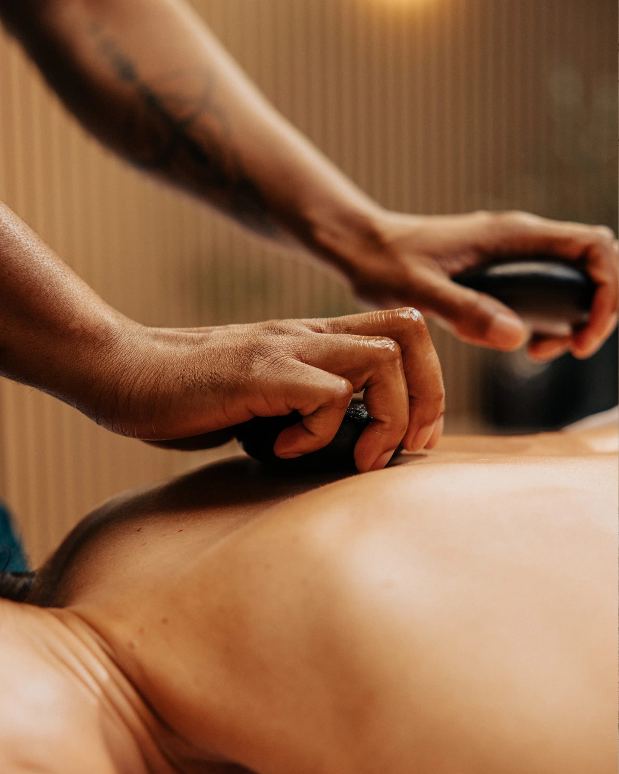 Close-up of warm stones being used to massage a client's back