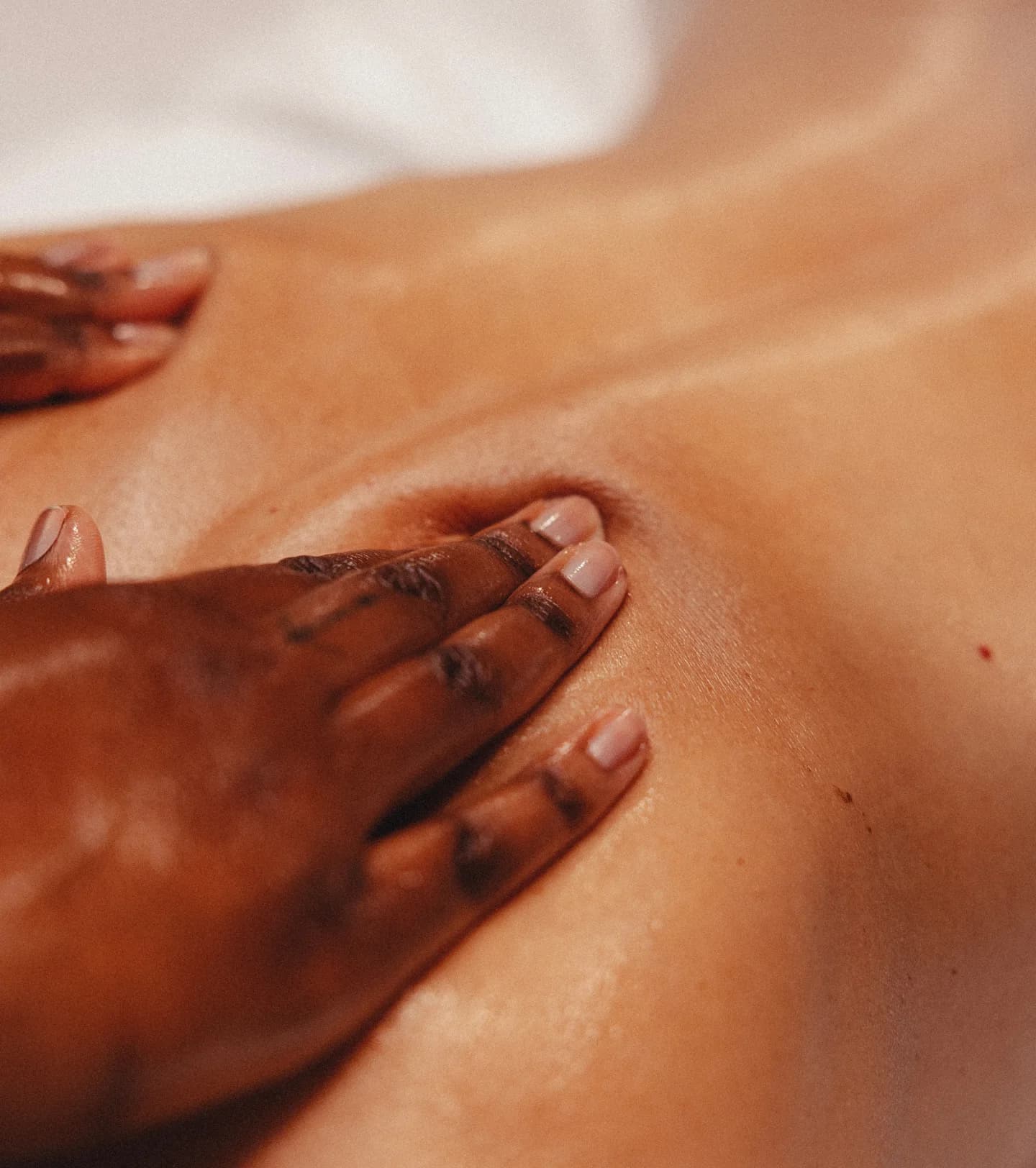 Close-up of a therapist's hands applying pressure to a client's back during a massage
