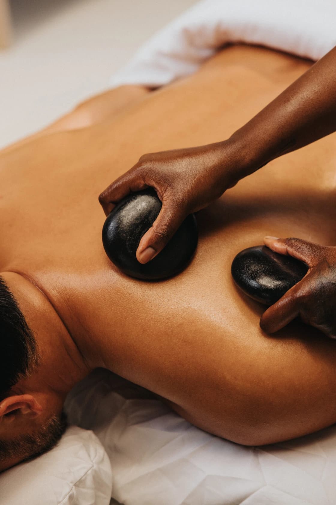 Therapist placing warm stones on a client's back during a hot stone massage