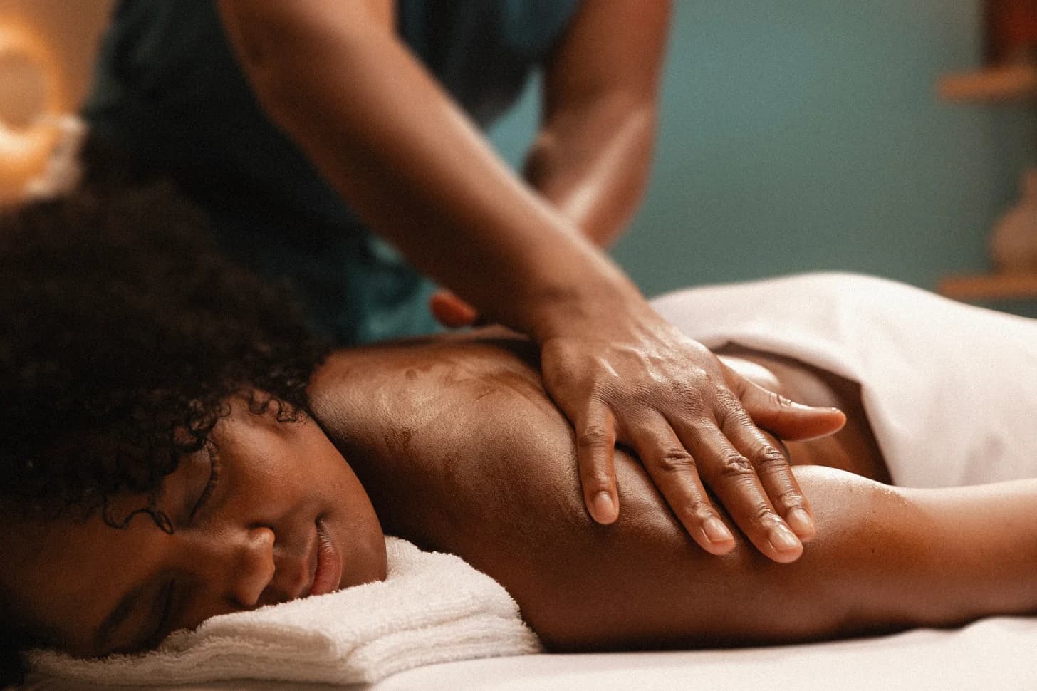 Woman with a soft smile, eyes closed and at ease, receiving a classic back massage